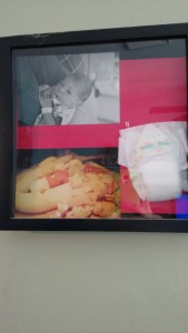 A shadow box with 2 pictures and a diaper