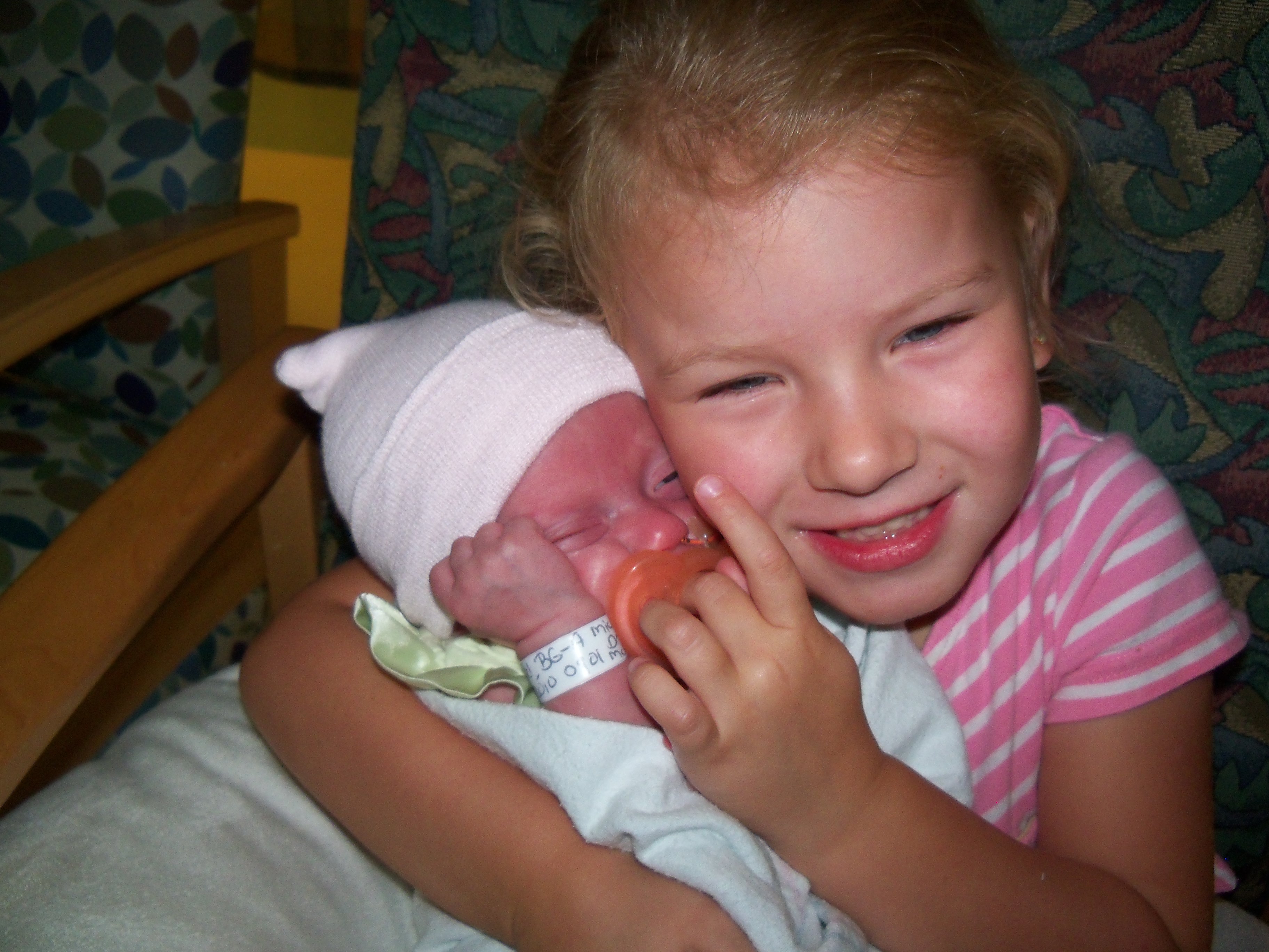older sibling holding preemie baby sister