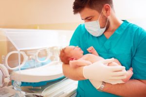 Male nurse holds baby in NICU