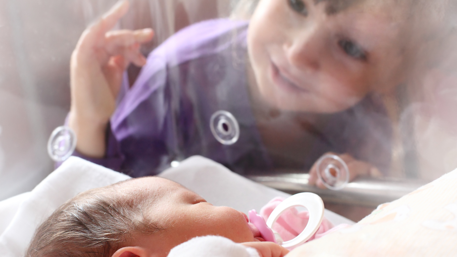 Young child visiting NICU sibling, hand to hold NICU support, NICU baby